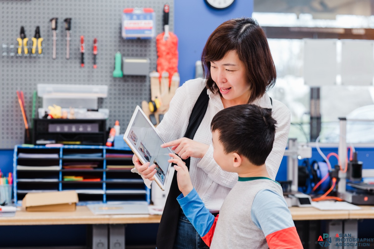 A KindleWood facilitator and a young learner exploring a tablet together in the studio.